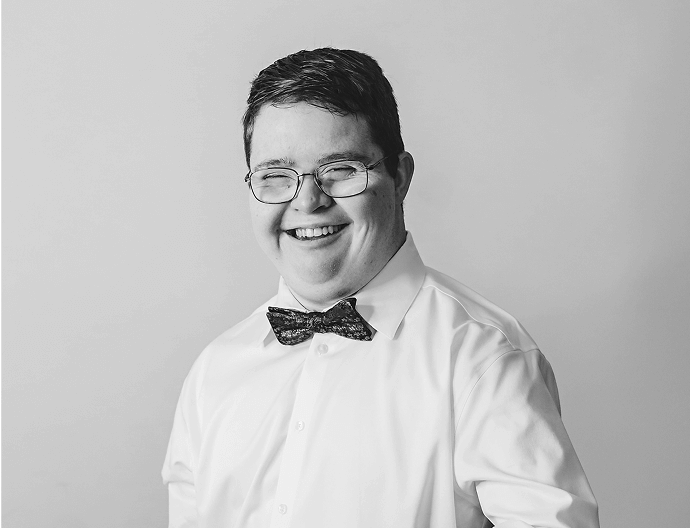 Young man in a a white shirt and a bowtie, with a huge smile
