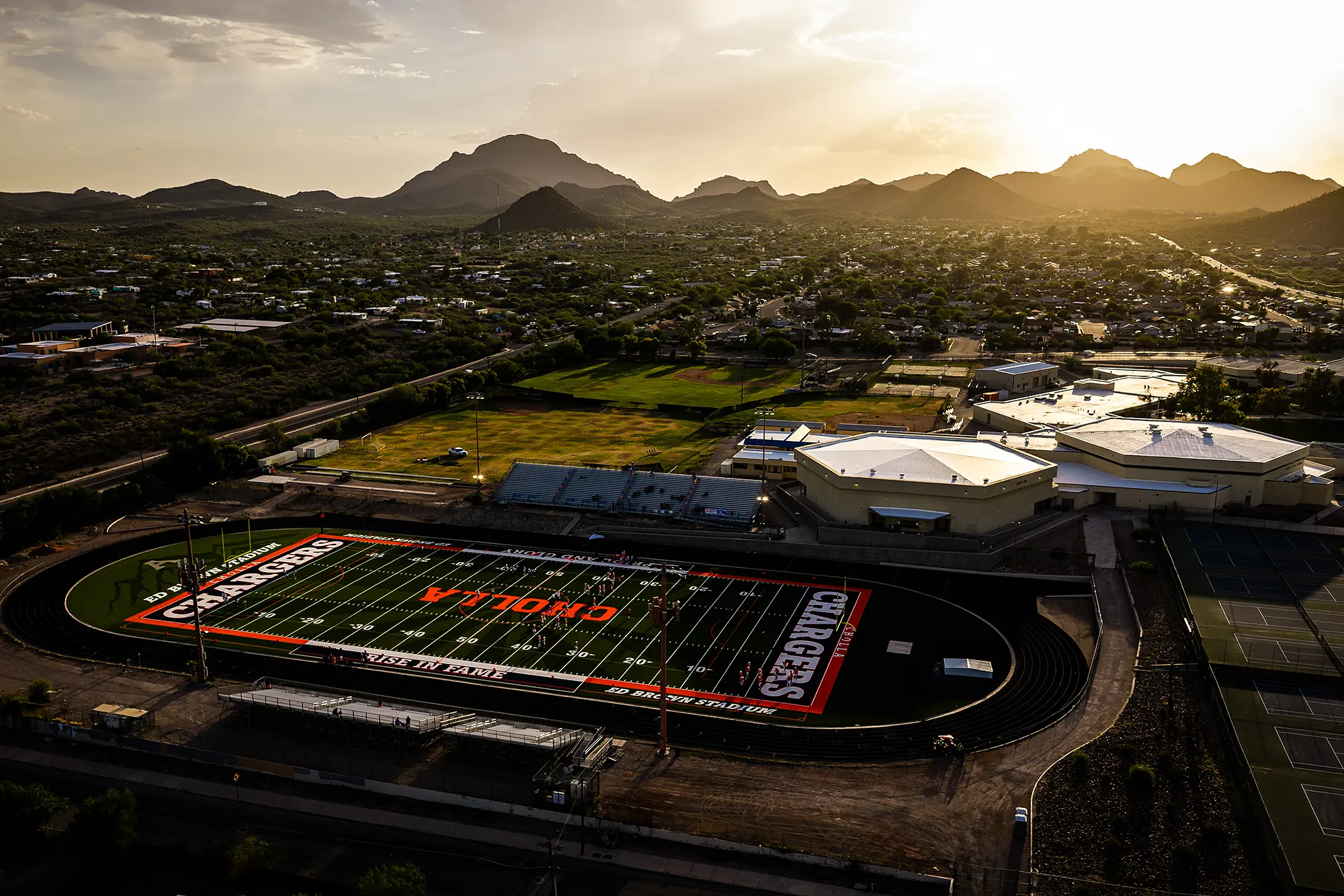 Aerial view at sunset of the Cholla High School campus and new football field in Tucson, Arizona, with the Tucson Mountains behind it