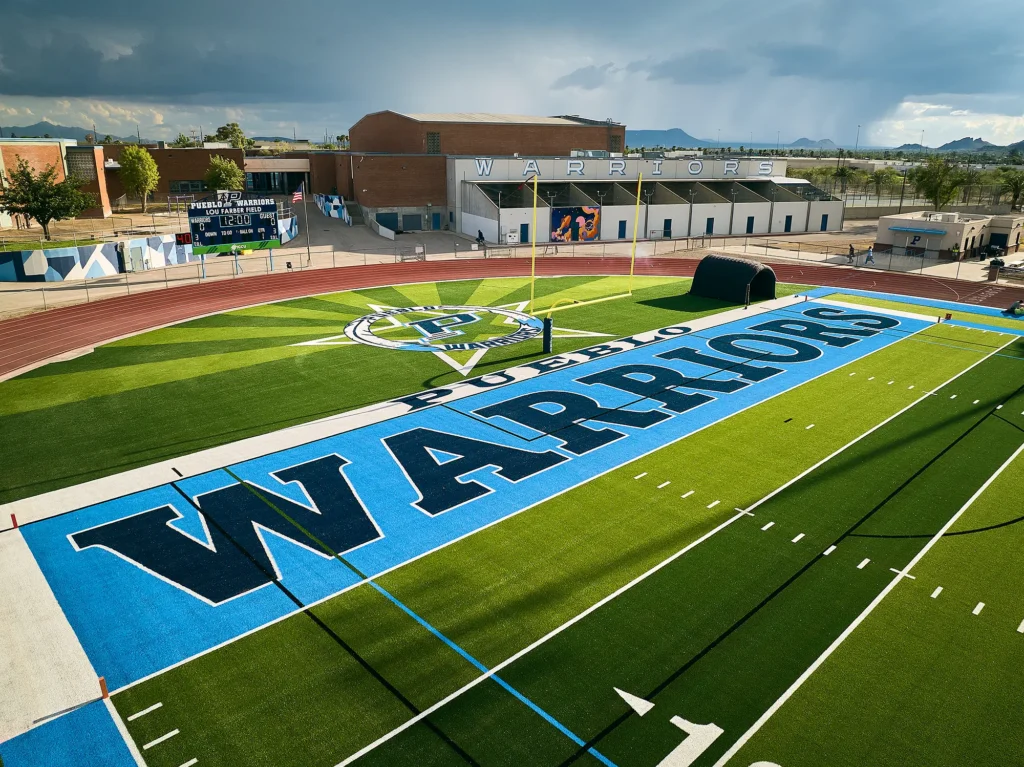 Close aerial view of the Pueblo Warriors end zone, with starburst graphic inlaid in the turf.